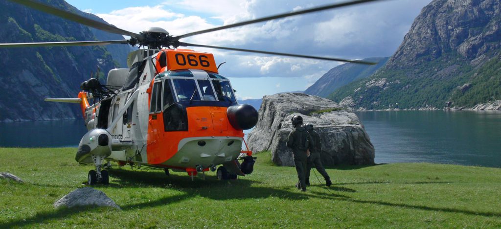 Bilde av seaking helikopter og person med fjord og fjell i bakgrunnen