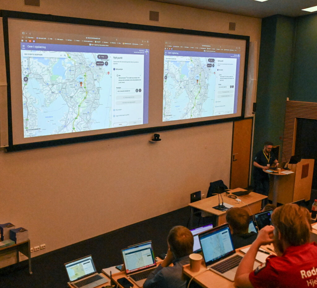 Dobbel storskjerm i et auditorium viser kartutsnitt fra dataverktøy 