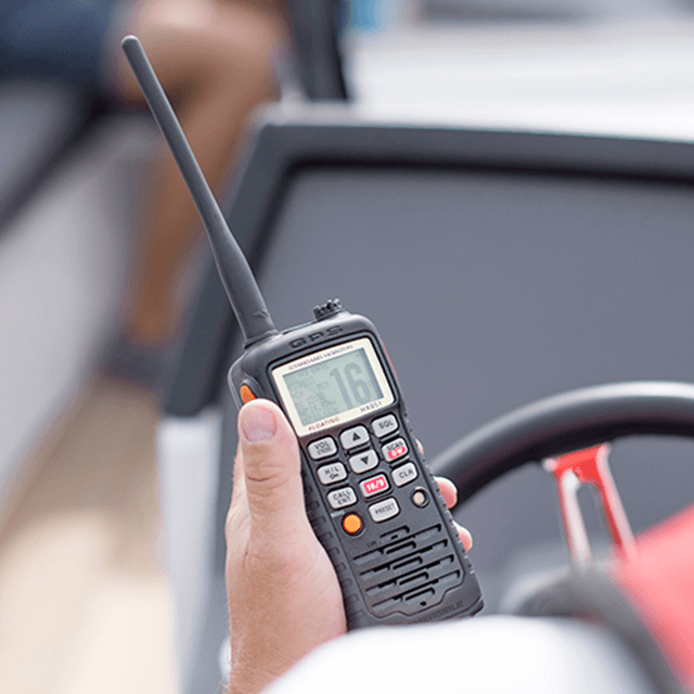 Håndholdt VHF En perssom som styrer en båt holder en håndholdt VHF i hånda.