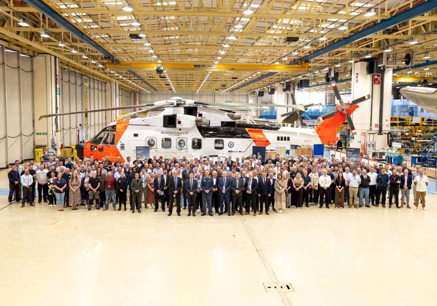 NAWSARH Celebration Event En veldig stor gruppe mennesker står foran et helikpoter inni en produksjonshall.
