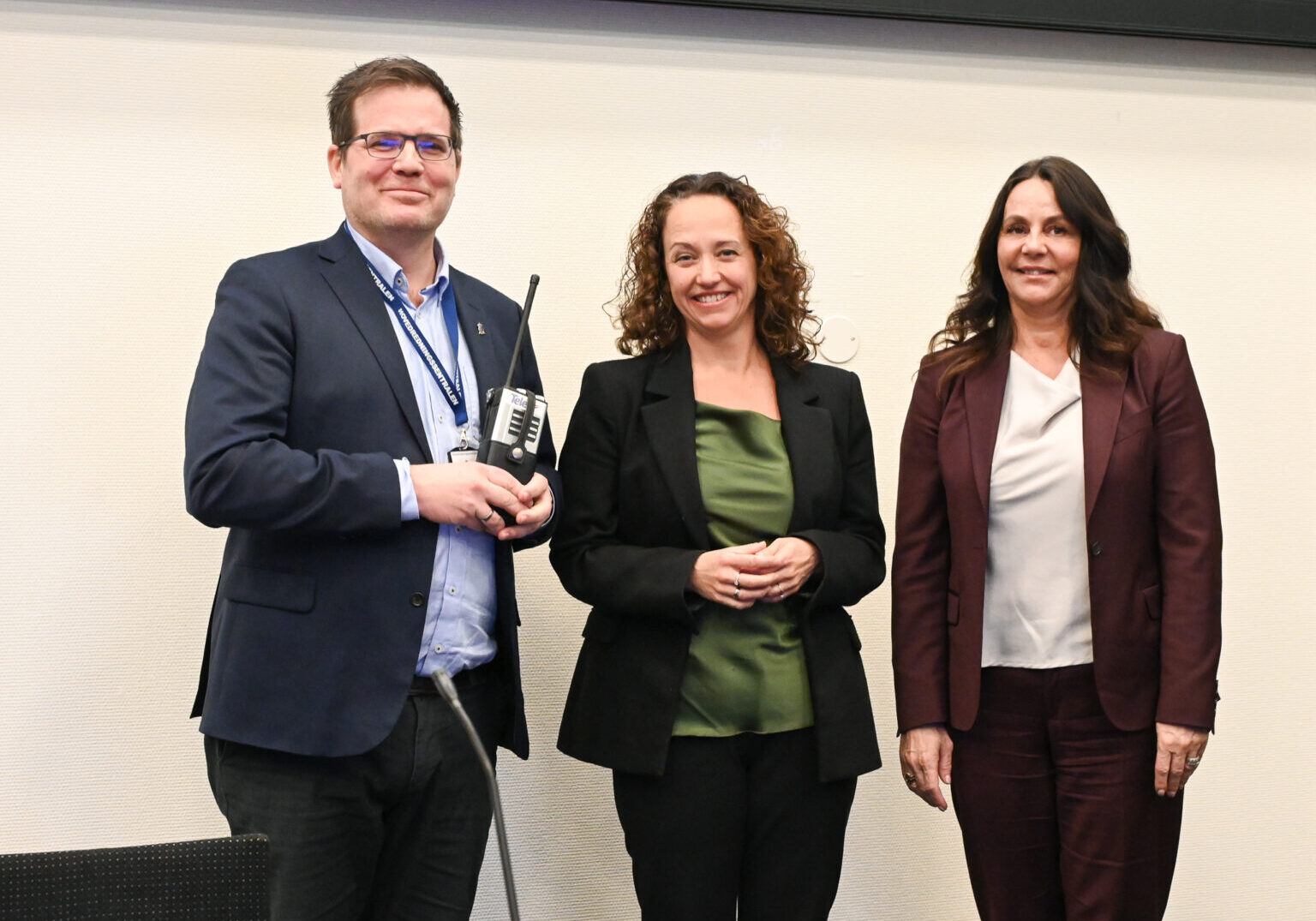 Tre personer står ved siden av hverandre og ser på kamera