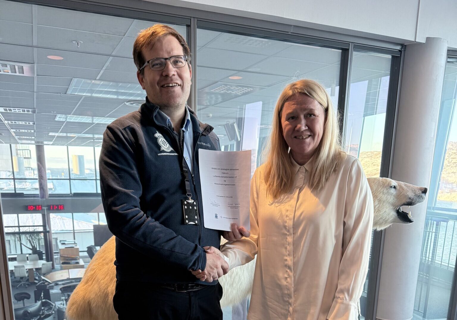 Randi og Jon, samarbeidsavtale En mann og en kvinne står foran en isbjørn og holder et dokument.