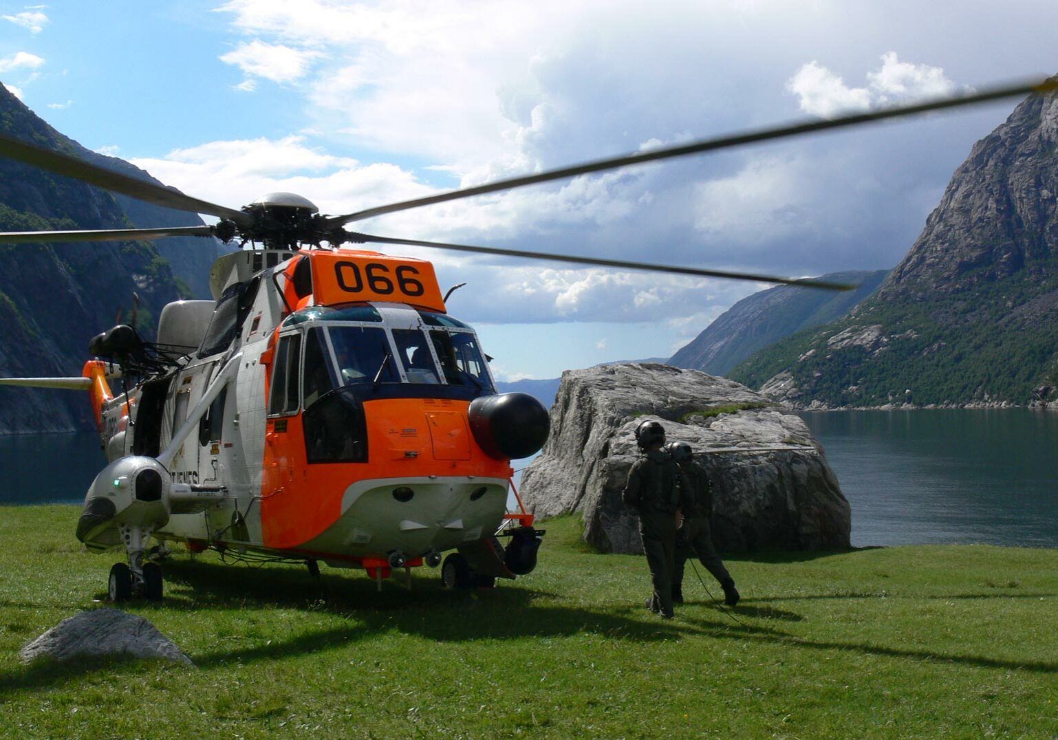 hrs-seaking Seaking helikopter og to personer med fjell og fjord i bakgrunn.